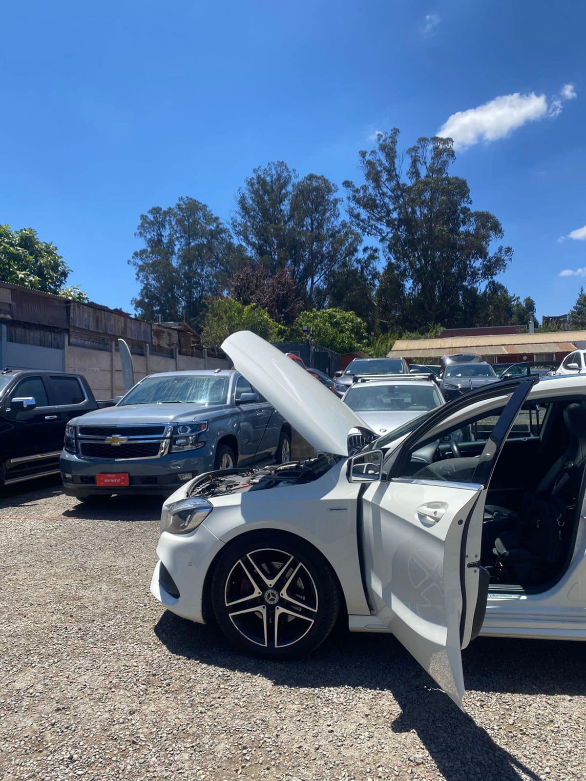 Revisión de un auto blanco con capó y puerta abiertos