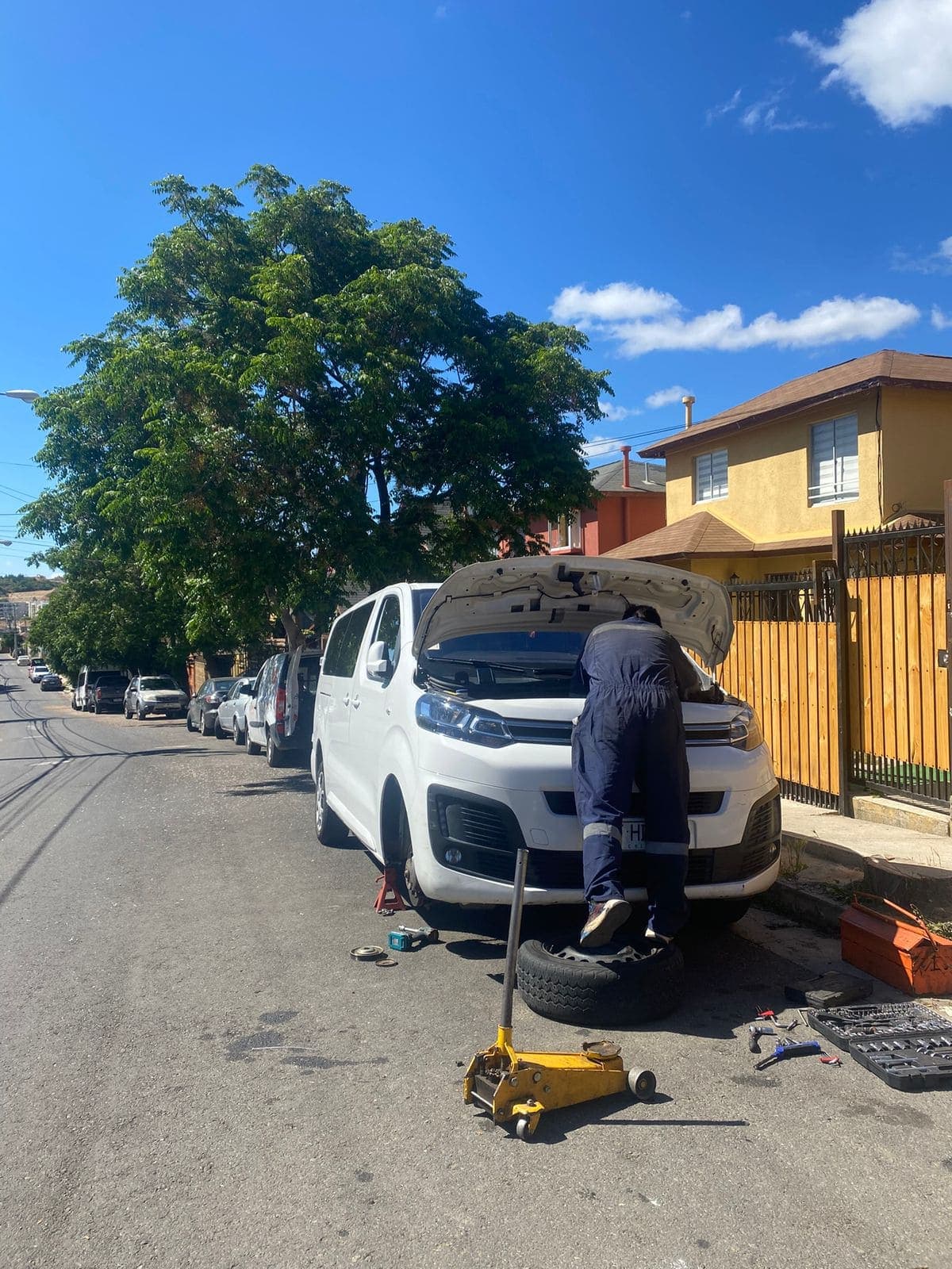 Mecánico revisando una furgoneta blanca levantada con gata